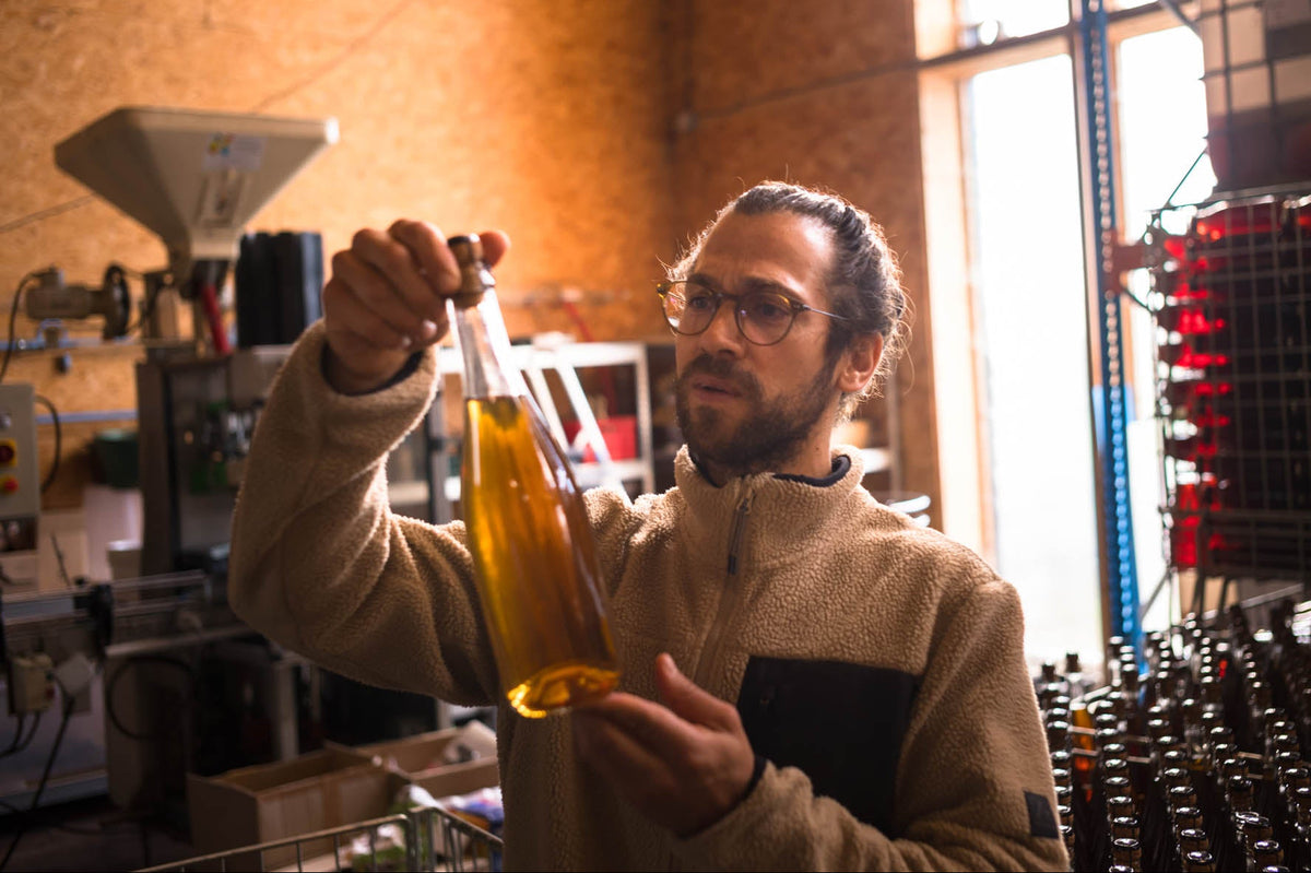 Aymeric Lemarchand examine une bouteille à la lumière dans l’atelier